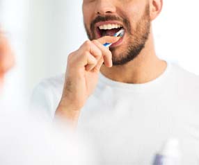 Man with dental implants in Tyler, TX brushing his teeth