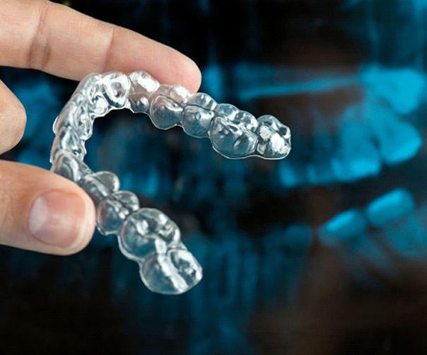 close up of a hand holding an Invisalign aligner
